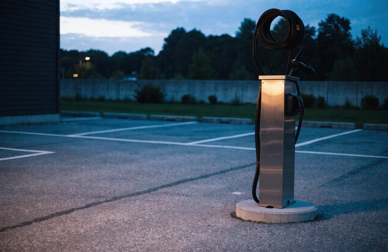Ein einzelnes AC-Ladeterminal auf einem Fundament auf einem leeren Parkplatz.
