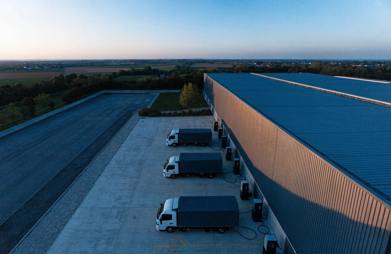 Luftaufnahme eines Logistikdepots mit E-Lkw an Ladepunkten
